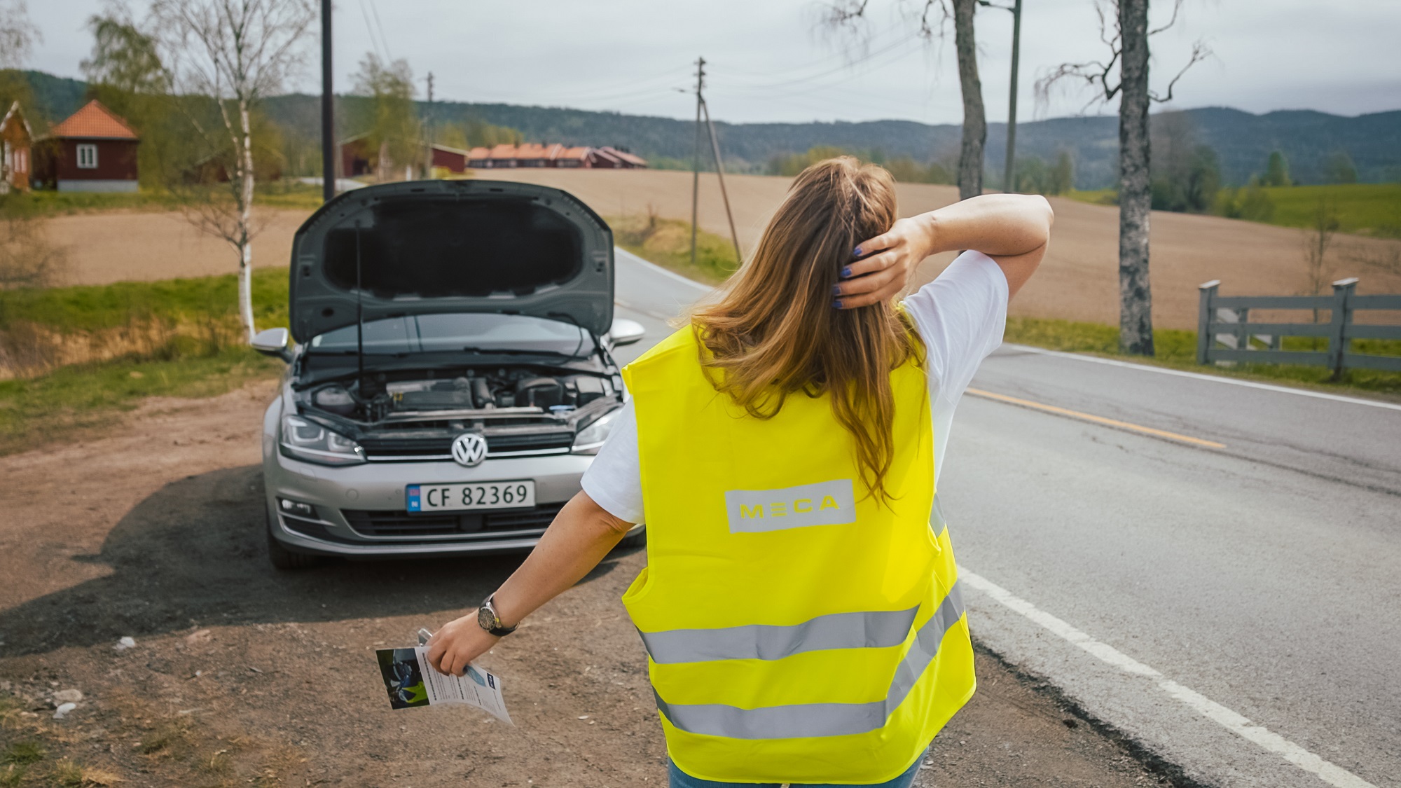 Jente i gul refleksvest har fått motorstopp på bilen og trenger MECA veihjelp