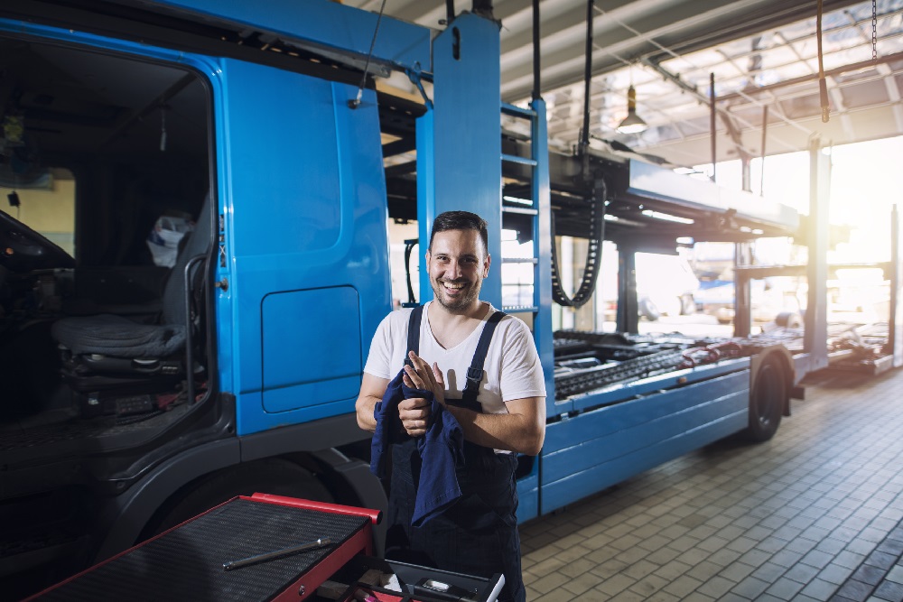 Mekaniker på et MECA Tungbil verksted ved blå trailer