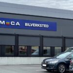 Utvendig grått, moderne verkstedbygg med MECA Bilverksted skilt på veggen